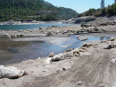 1986 Ford Bronco - A scenic view of a lake surrounded by rocks and trees under a clear blue sky.