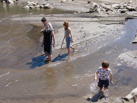1986 Ford Bronco - Children explore a muddy, watery area with rocks and tire tracks visible.