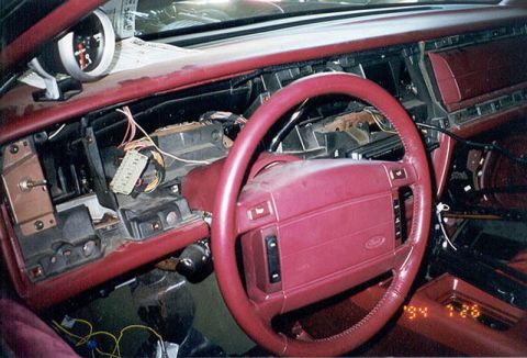 1992 Ford Crown Victoria - Interior view of a Ford with a red steering wheel bearing the Ford oval, showing the dashboard partially disassembled with the center dash…