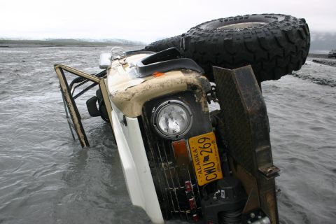 2003 Jeep TJ - Overturned Jeep Wrangler submerged in shallow water with Alaska license plate.