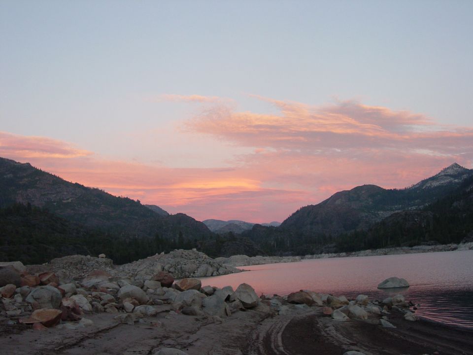 Scenic landscape with mountains, a lake, and a colorful sky at dusk