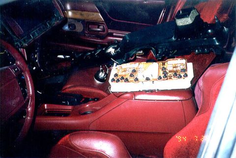 1992 Ford Crown Victoria - Interior of a car mid-disassembly with red leather seats and console, a red leather-wrapped steering wheel, and the dashboard partly remove…