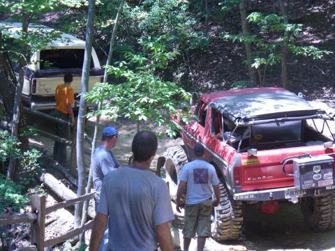 1996 Ford Bronco - Two Ford Broncos navigate a challenging off-road trail in a wooded area.
