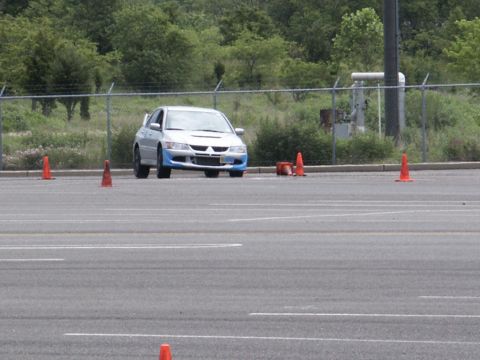 2001 Mercury Grand Marquis - A silver sedan with blue accents drives on a paved course marked by orange cones.