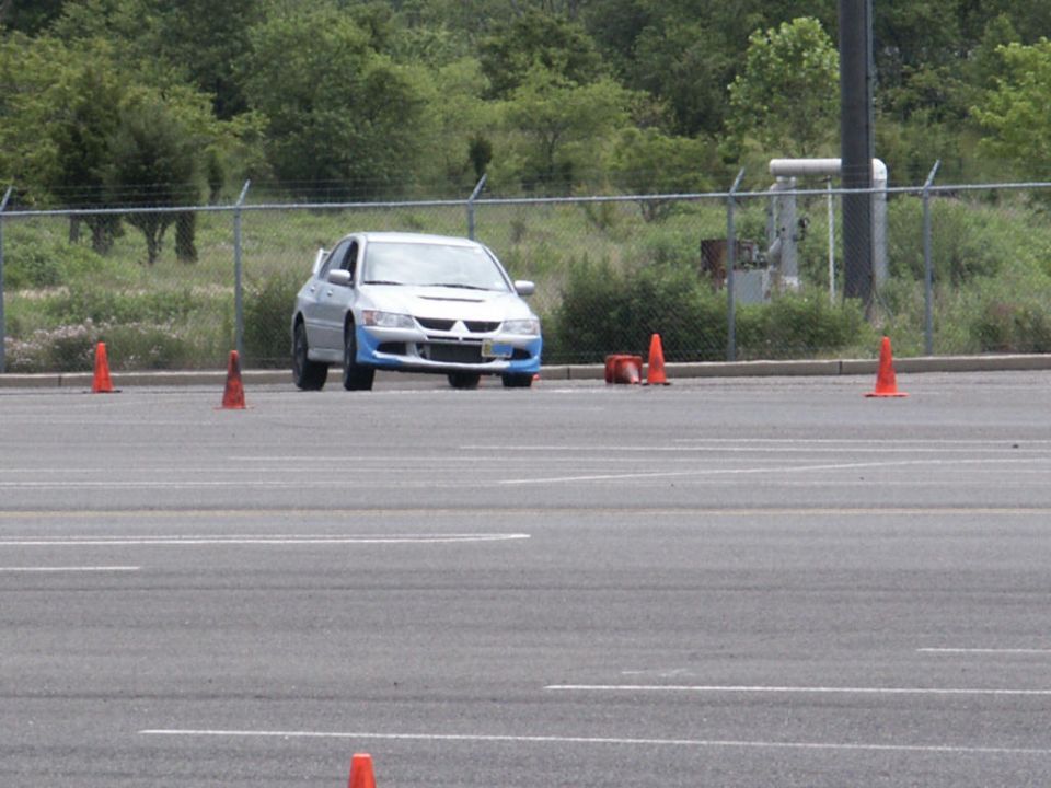 Silver sedan with blue front bumper and side skirts on asphalt course with orange cones