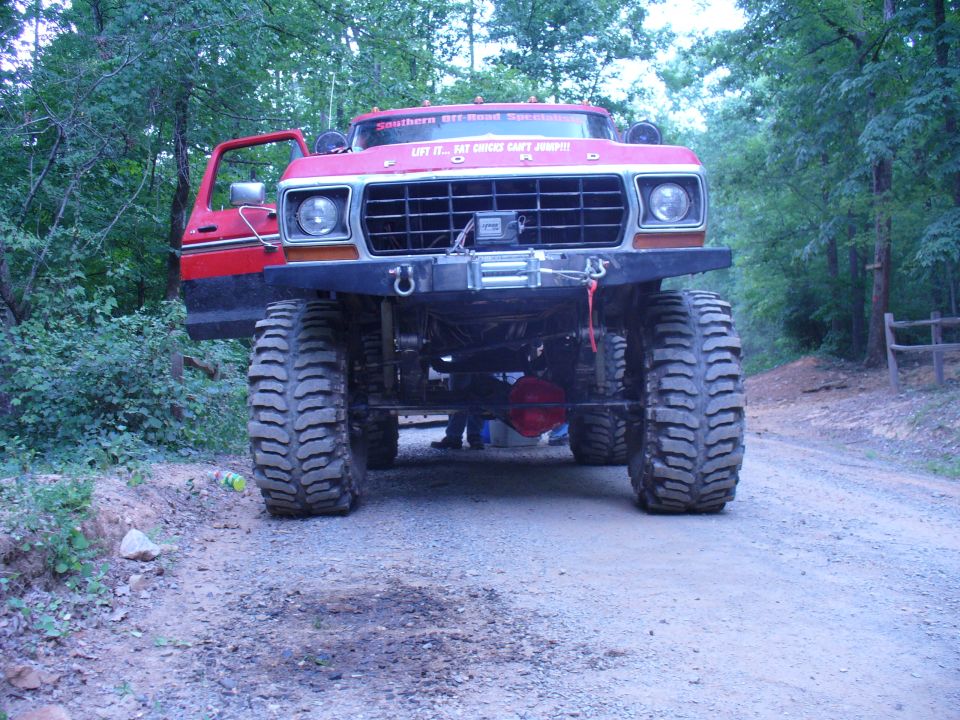 Red Ford truck with massive off-road tires and a winch on the front bumper