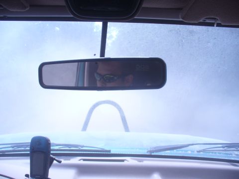 1996 Ford Bronco - The view from inside the vehicle shows a driver reflected in the rearview mirror, with a GPS device mounted on the dashboard.
