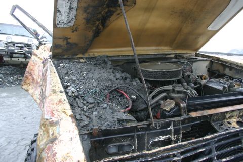 2003 Jeep TJ - This vehicle's engine compartment is heavily contaminated with mud and debris, obscuring the engine components.