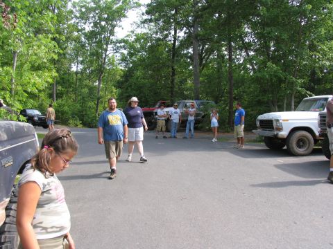 1995 Ford C-350 (Centurion Conversions) - A white Ford F-Series truck is parked in a wooded area alongside other vehicles and people.