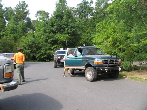1995 Ford C-350 (Centurion Conversions) - A green pickup truck is parked in a lot with other vehicles and trees in the background.