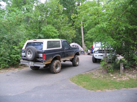 1995 Ford C-350 (Centurion Conversions) - Two trucks are parked at a campsite with tents in the background.