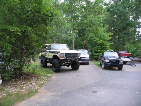 1995 Ford C-350 (Centurion Conversions) - A lifted 1978 Ford Bronco is parked in a lot with other vehicles and a trailer.