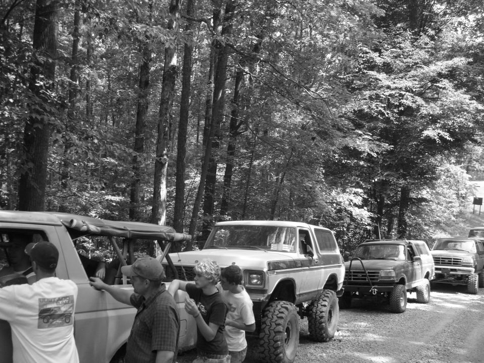 White Ford Bronco with lifted suspension and large tires, parked on a dirt road