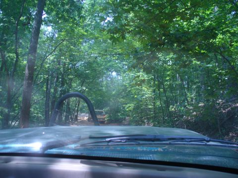 1996 Ford Bronco - Driving on an off-road trail through a wooded area with other vehicles ahead.