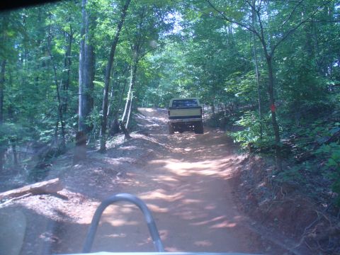 1996 Ford Bronco - A yellow 1996 Ford Bronco navigates a wooded trail, seen from another vehicle.