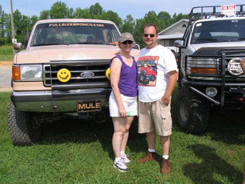 1995 Ford C-350 (Centurion Conversions) - A couple poses in front of a lifted tan Ford F-Series truck and a white Ford F-Series truck with a "FOR SALE" sign.