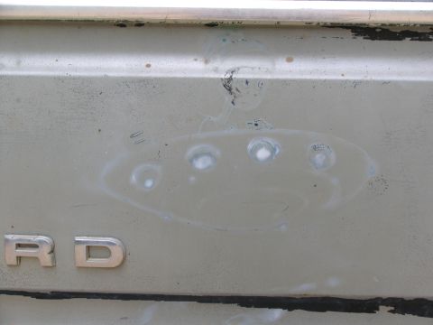 1995 Ford C-350 (Centurion Conversions) - The rear panel of a vehicle displays the 'Ford' lettering, with several circular indentations visible on the surface.