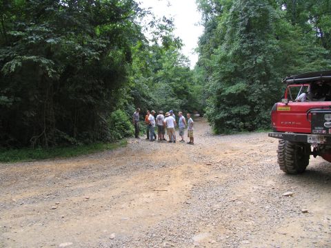 1995 Ford C-350 (Centurion Conversions) - Group of people gathered on a dirt road next to a red Ford truck.