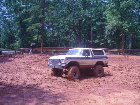 1996 Ford Bronco - Ford Bronco navigates a muddy off-road course surrounded by trees.