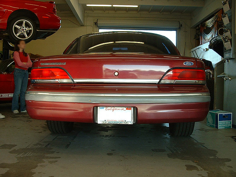 Rear view of a dark red Ford Crown Victoria LX parked inside a shop