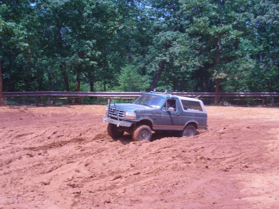 Dark green Ford Bronco stuck in mud, front bumper guard, roof rack