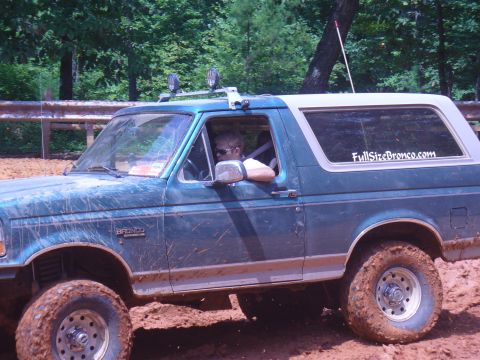 1996 Ford Bronco - Muddy 1996 Ford Bronco navigates an off-road trail with a driver behind the wheel.