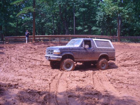 1996 Ford Bronco - A Ford Bronco navigates a muddy terrain, its tires deep in the mire.