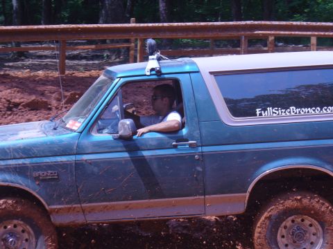 1996 Ford Bronco - A teal Ford Bronco navigates a muddy off-road course.