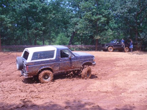 1996 Ford Bronco - Ford Bronco navigating a muddy off-road course with another truck visible in the background.