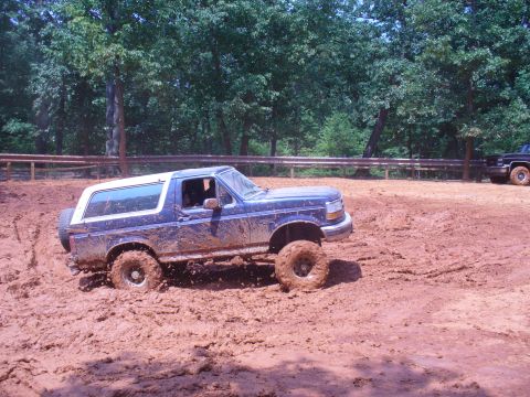 1996 Ford Bronco - A blue Ford Bronco navigates a muddy off-road course.