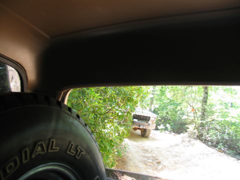 1995 Ford C-350 (Centurion Conversions) - Pickup truck driving on a dirt road surrounded by trees.