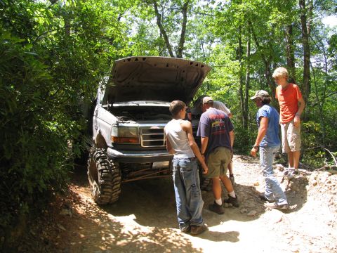 1995 Ford C-350 (Centurion Conversions) - Group of people examining the engine of a lifted 1995 Ford C-350 off-road truck.