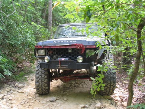 1995 Ford C-350 (Centurion Conversions) - Modified Ford F-Series truck with "ALASKAN EXTREME" text on the hood, seen on a wooded trail.