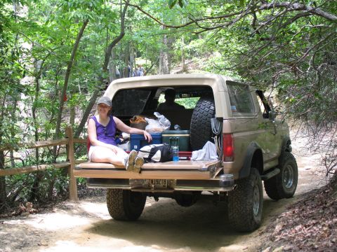 1995 Ford C-350 (Centurion Conversions) - Person relaxing in the back of a Ford Bronco on an off-road trail.