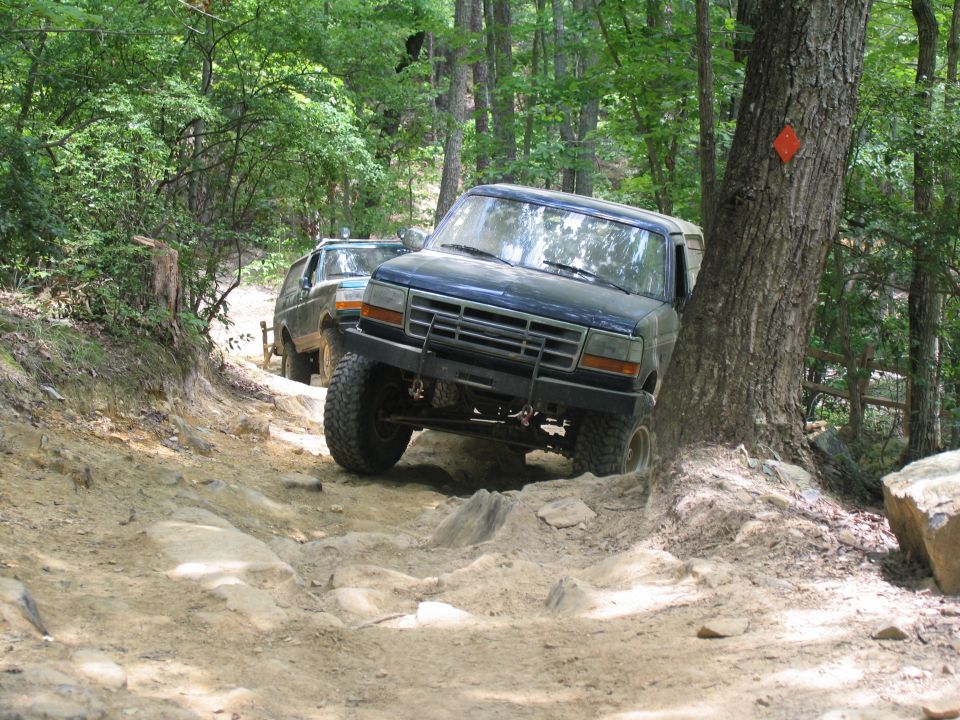 Dark blue 1990s Ford truck on rocky trail, another vehicle behind