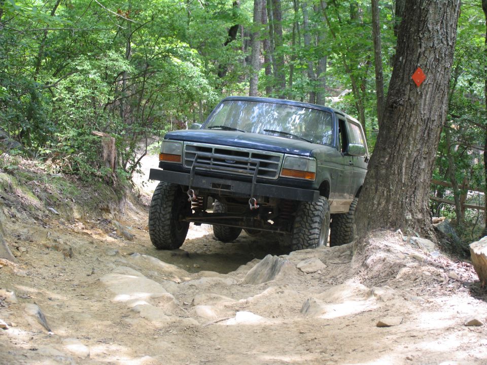 Blue SUV with aftermarket bumper on a rocky off-road trail