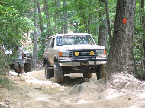 1995 Ford C-350 (Centurion Conversions) - Ford Bronco navigates a challenging off-road trail with another vehicle following.