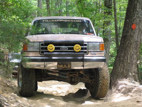 1995 Ford C-350 (Centurion Conversions) - This tan Ford truck, identified by its "MULE" license plate and "FULLSIZEBRONCO.COM" banner, navigates an off-road trail.