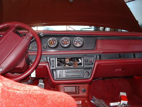1992 Ford Crown Victoria - Red interior of a Ford sedan under reassembly, viewed from the passenger side across the dash: three aftermarket Auto Meter gauges includin…