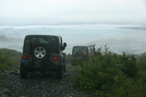 2003 Jeep TJ - Two Jeep TJs drive on a gravel road towards a glacier under a cloudy sky.