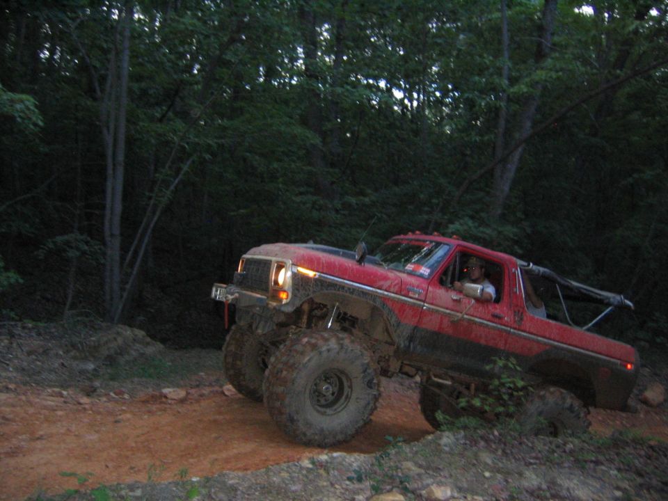 red lifted truck with large tires on a dirt trail