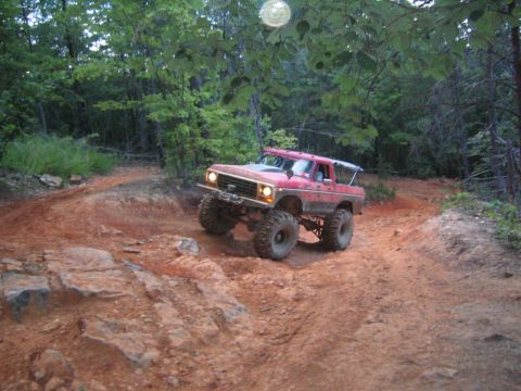 1979 Ford Bronco - A red Ford Bronco navigates a rocky, wooded trail.