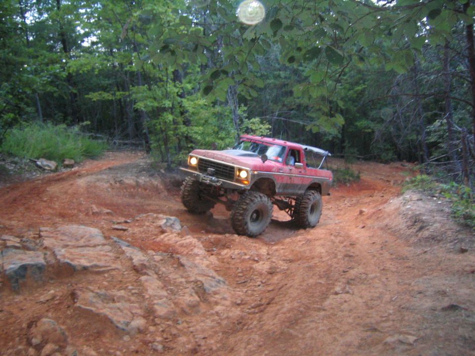 Red 1978 Ford Bronco with large tires on a dirt trail