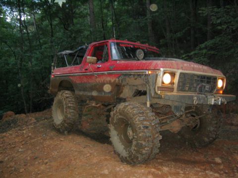 1979 Ford Bronco - This modified SUV is shown on a muddy trail surrounded by trees.