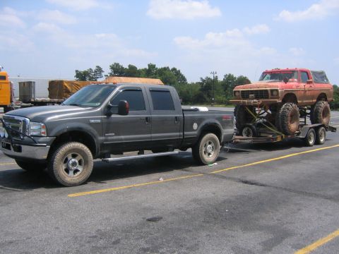1979 Ford Bronco - A lifted red Ford Bronco is transported on a trailer behind a grey Ford F-250 truck.