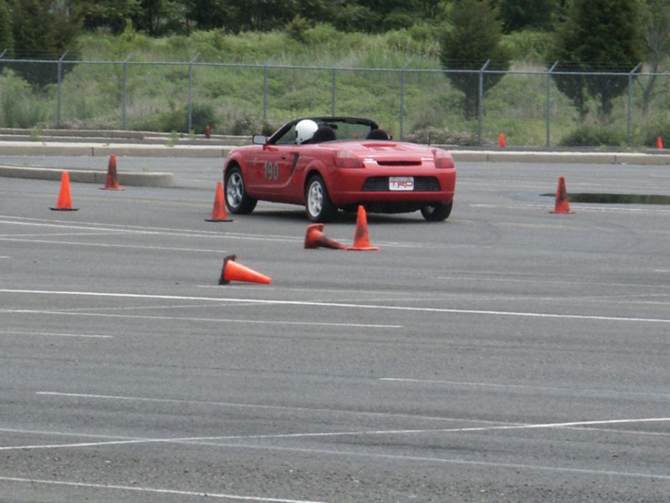 Red convertible sports car with number 190 on door navigating a cone course
