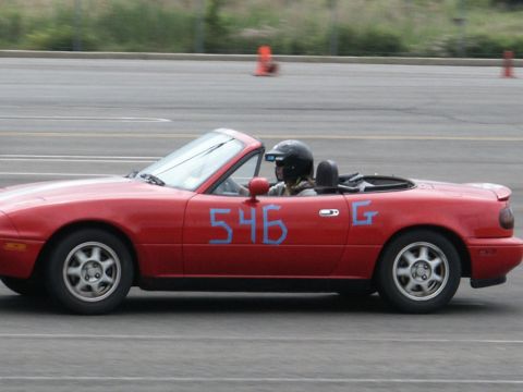 2001 Mercury Grand Marquis - A red convertible sports car with blue racing numbers is seen on a track.