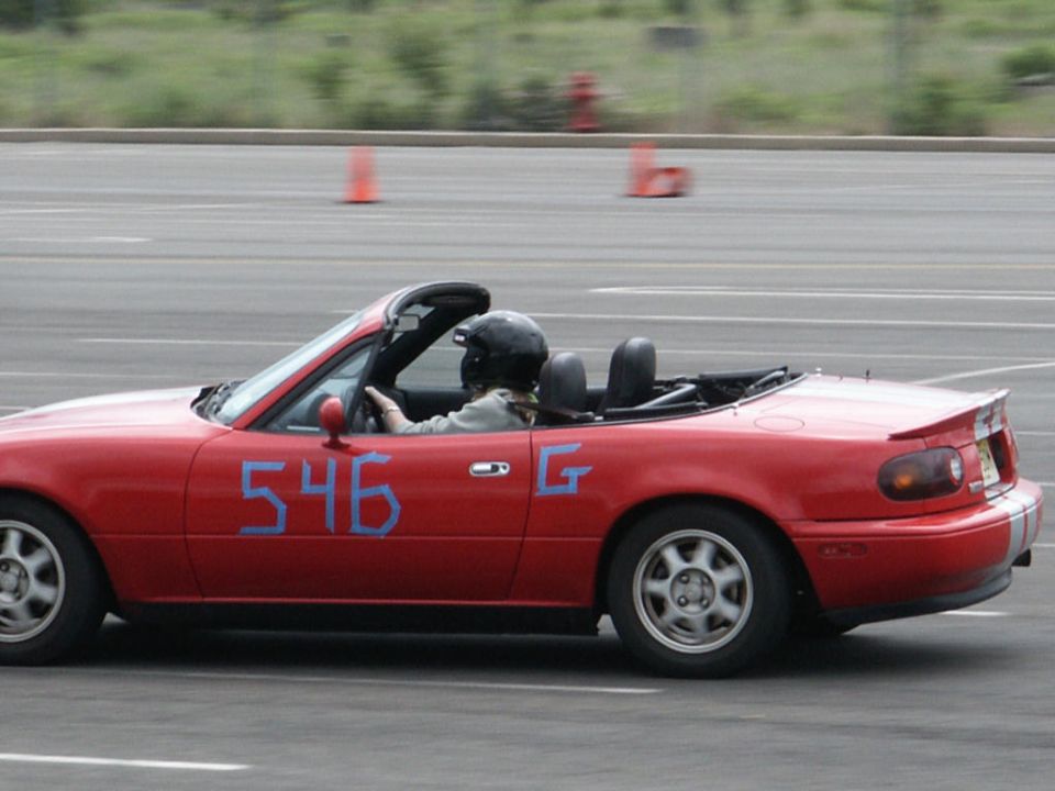 Red convertible sports car with blue number 546 on door, driver wearing helmet