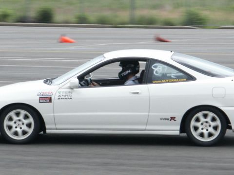 2001 Mercury Grand Marquis - A white coupe with racing decals is seen on a track with a driver wearing a helmet.