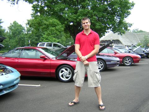 1995 Ford Probe - A man poses in front of several Ford Probe models at an outdoor car show.